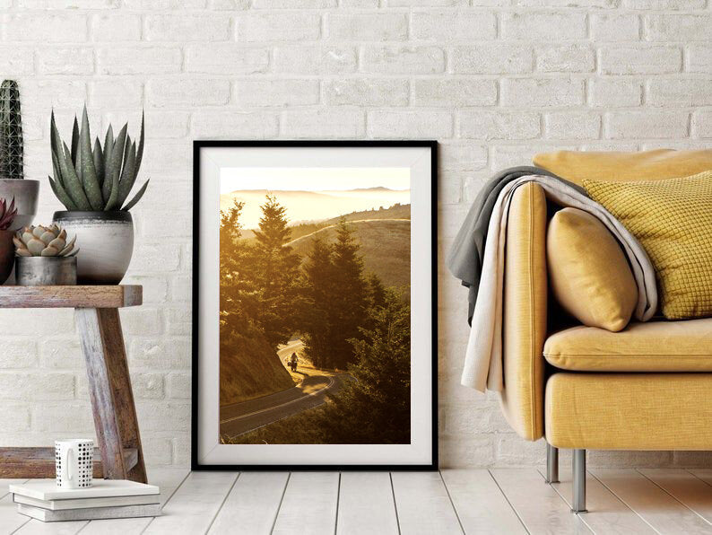 Around the Bend- A photograph by Mark McInnis in a black fame next to a yellow couch.