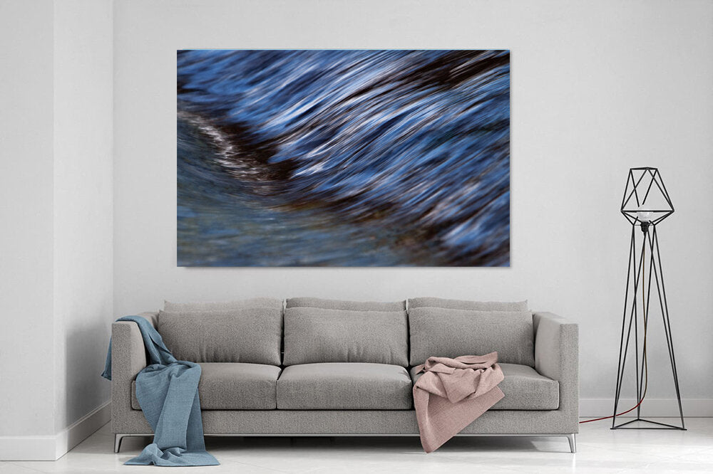 River Wave- A photograph by Mark McInnis above a couch.