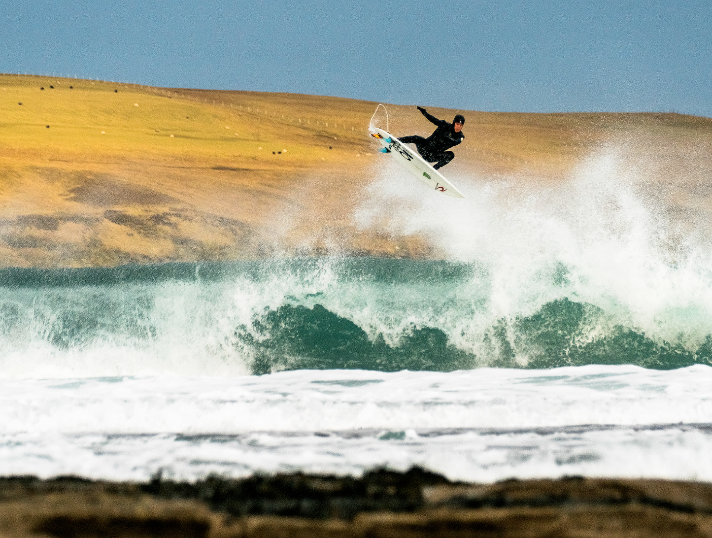 Alba- A photo book by Mark McInnis- Surfer getting an air with a rolling hillside in the background